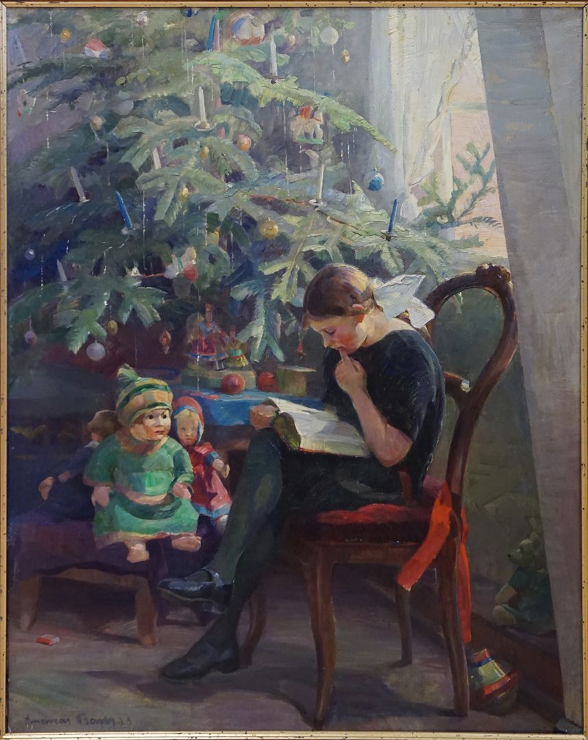 Girl reading in front of the Christmas tree 