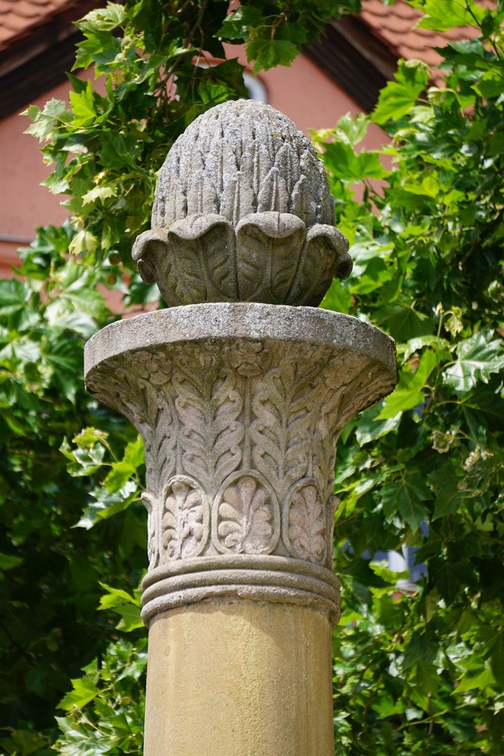 Pferdebrunnen Brunnensäule mit einem ägyptisierenden Kapitell und Pinienzapfen als Bekrönung