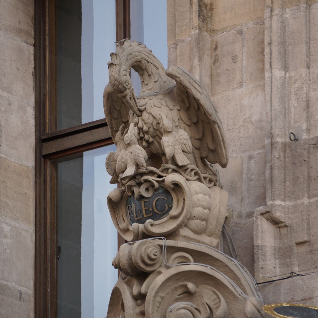 Central portal Crowning pelican with inscription: "P.L.E.G." = Prudentia Legibus Et Gratia / with wisdom, justice and goodness
